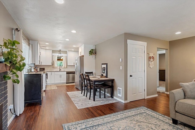 living area featuring baseboards, visible vents, dark wood finished floors, and recessed lighting