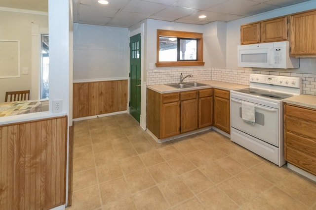 kitchen featuring white appliances, brown cabinets, light countertops, a paneled ceiling, and a sink