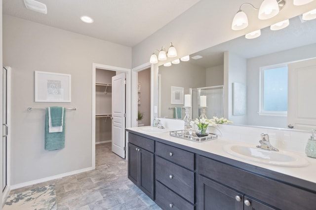 bathroom with a stall shower, a sink, a spacious closet, and double vanity