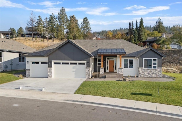 view of front of house with concrete driveway, an attached garage, a front yard, a standing seam roof, and stone siding