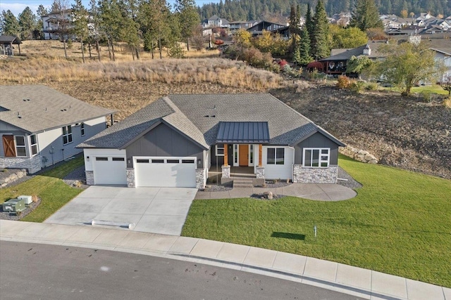 view of front of home featuring a garage, a shingled roof, stone siding, driveway, and a front lawn