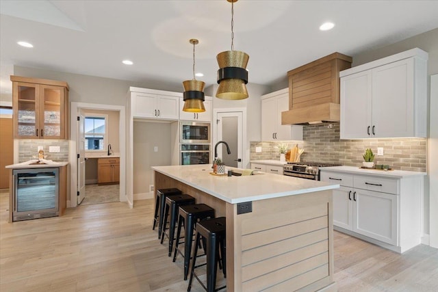 kitchen featuring beverage cooler, stainless steel appliances, light wood finished floors, and a sink