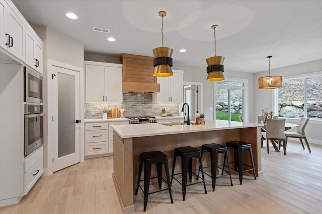 kitchen featuring a sink, visible vents, light wood-style floors, light countertops, and appliances with stainless steel finishes