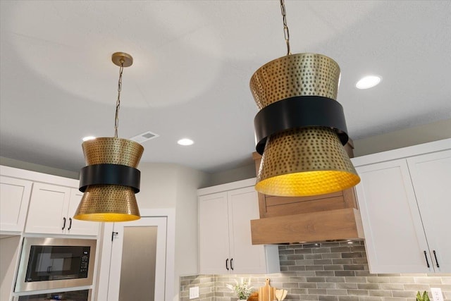 room details with white cabinetry, black microwave, and backsplash