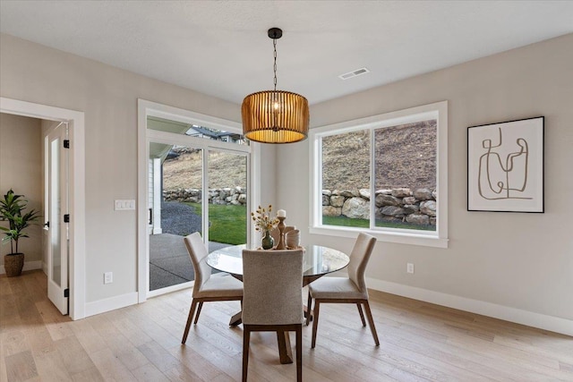 dining area featuring visible vents, light wood-style flooring, and baseboards