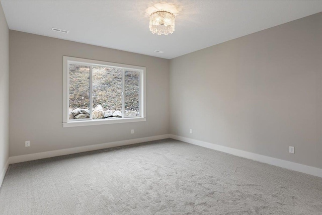 spare room featuring carpet floors, visible vents, and baseboards