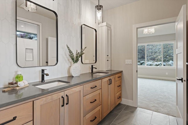 bathroom with double vanity, tile patterned flooring, baseboards, and a sink