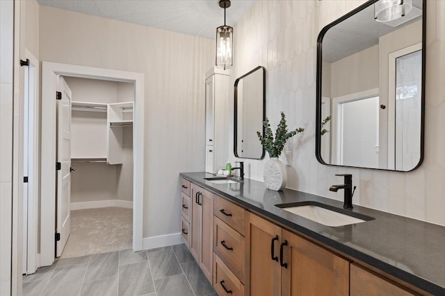 full bath featuring a sink, a spacious closet, baseboards, and double vanity