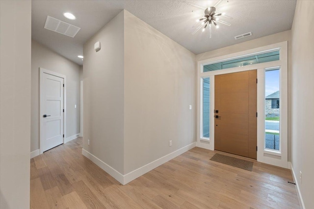 entryway with light wood finished floors, visible vents, and baseboards