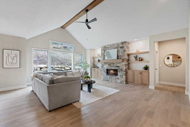 living area featuring ceiling fan, high vaulted ceiling, a fireplace, light wood-type flooring, and beam ceiling