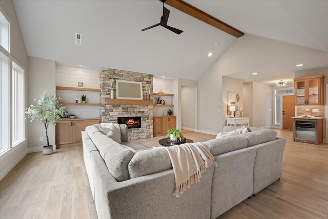 living area with ceiling fan, light wood-type flooring, wine cooler, and a fireplace