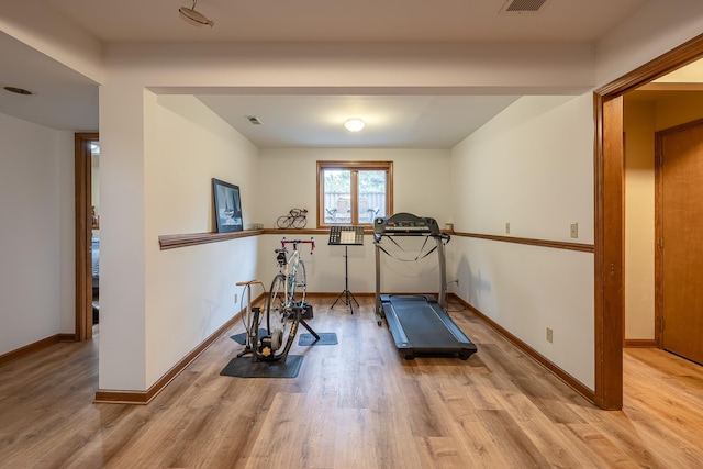 exercise room featuring wood finished floors, visible vents, and baseboards