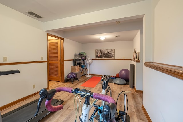 workout room featuring visible vents, baseboards, and wood finished floors