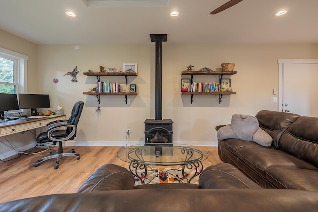 living area with baseboards, wood finished floors, a wood stove, and recessed lighting