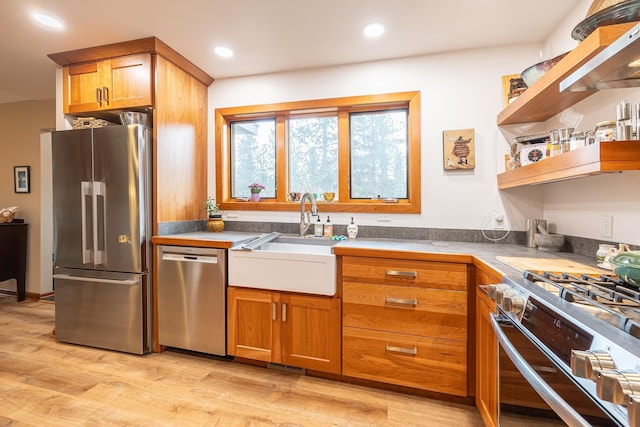 kitchen with brown cabinets, open shelves, light wood-style flooring, appliances with stainless steel finishes, and a sink