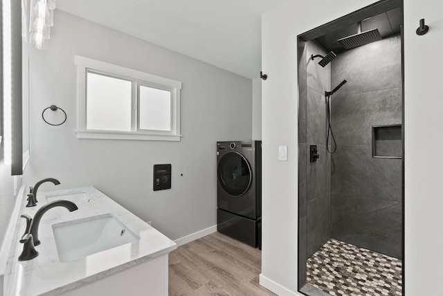 full bath with washer / dryer, a tile shower, a sink, and wood finished floors