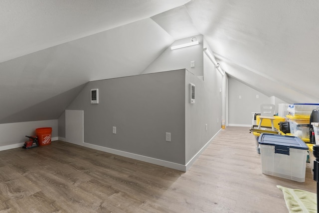 bonus room with vaulted ceiling, light wood finished floors, visible vents, and baseboards