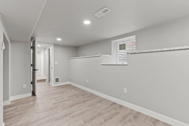 basement featuring light wood-style floors, visible vents, and baseboards