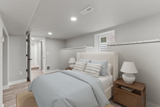 bedroom with light wood finished floors, recessed lighting, visible vents, and baseboards