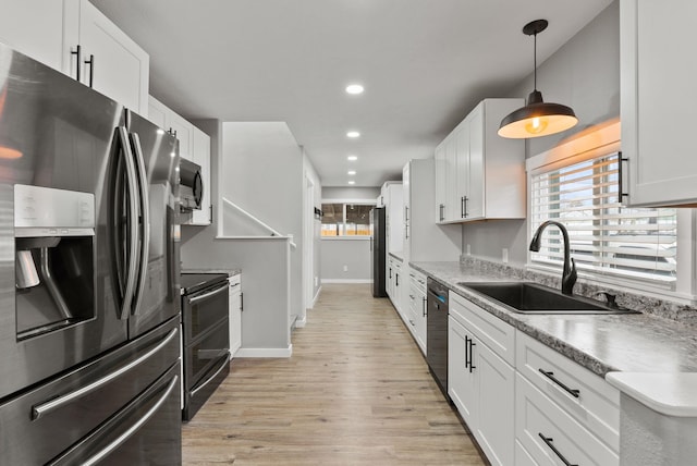 kitchen with recessed lighting, a sink, white cabinetry, light wood-style floors, and appliances with stainless steel finishes