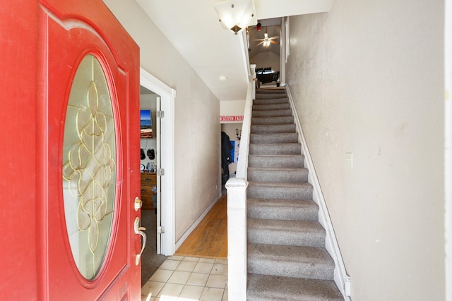 entrance foyer with stairway, light tile patterned flooring, and baseboards