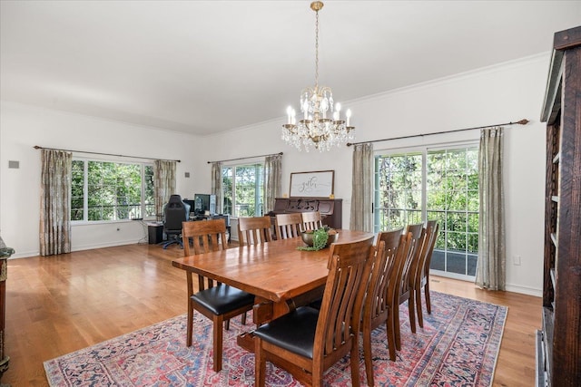 dining area with ornamental molding, baseboards, a notable chandelier, and light wood finished floors