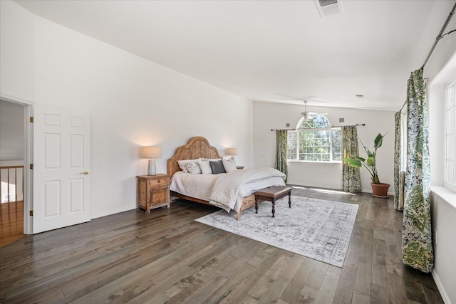 bedroom featuring baseboards, visible vents, vaulted ceiling, and dark wood finished floors