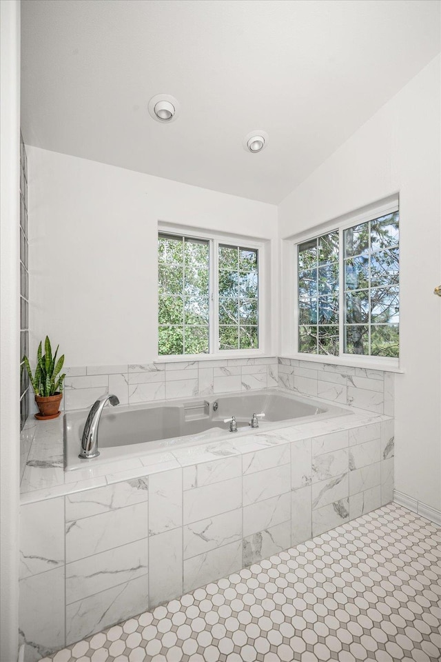 bathroom with vaulted ceiling, a bath, and a healthy amount of sunlight