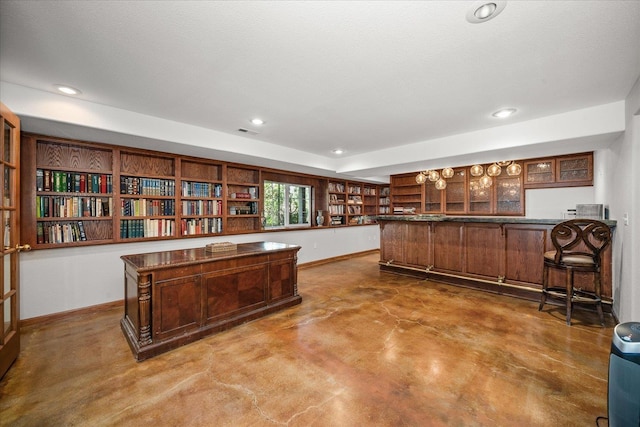 kitchen featuring dark countertops, glass insert cabinets, concrete floors, a peninsula, and baseboards