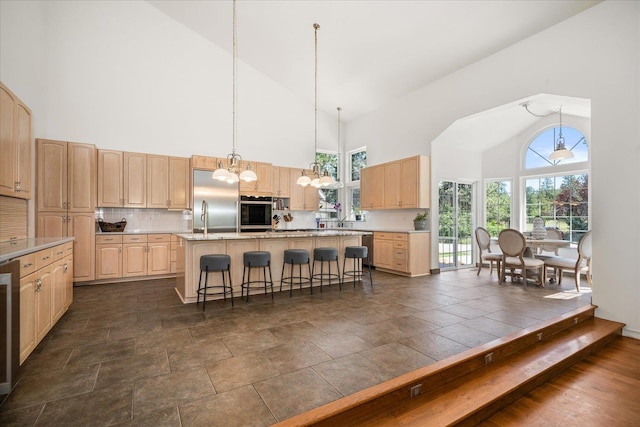 kitchen featuring stainless steel appliances, tasteful backsplash, a kitchen island, and light brown cabinetry