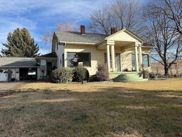 view of front of house with a front lawn, a chimney, and a shingled roof