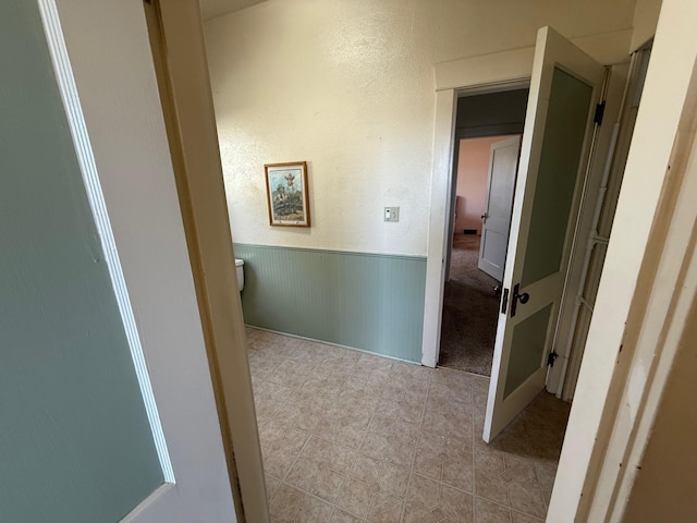 hallway with a textured wall and wainscoting