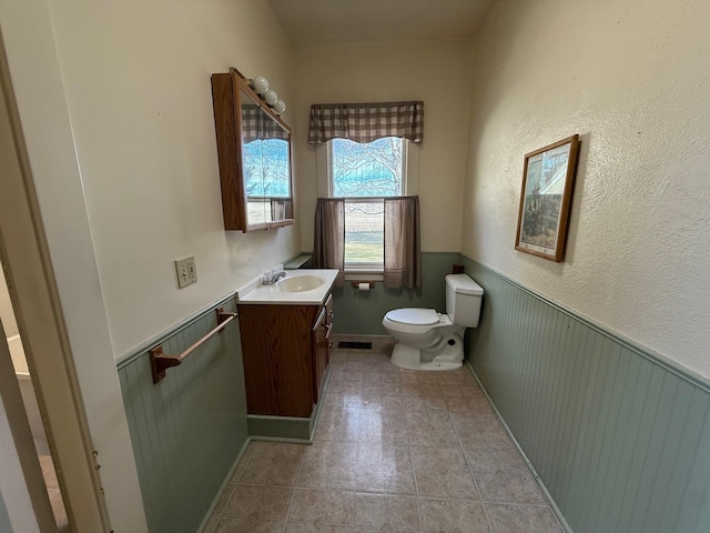 bathroom with wainscoting, vanity, toilet, and tile patterned floors