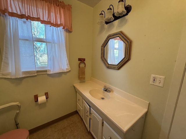 bathroom with toilet, vanity, and baseboards