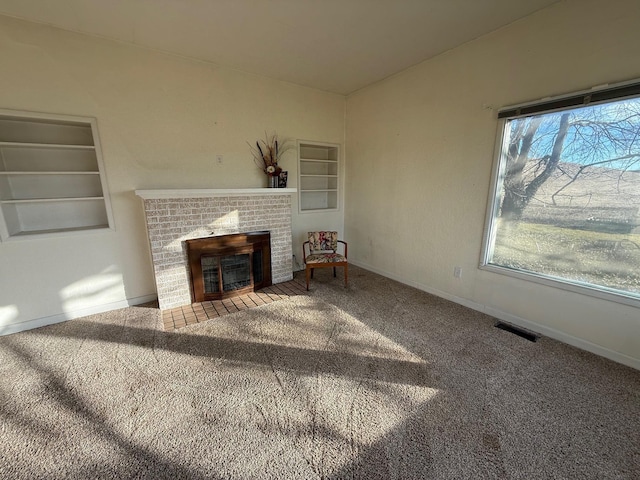 interior space with baseboards, visible vents, carpet flooring, built in shelves, and a fireplace