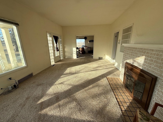 interior space with a wealth of natural light, a brick fireplace, and visible vents