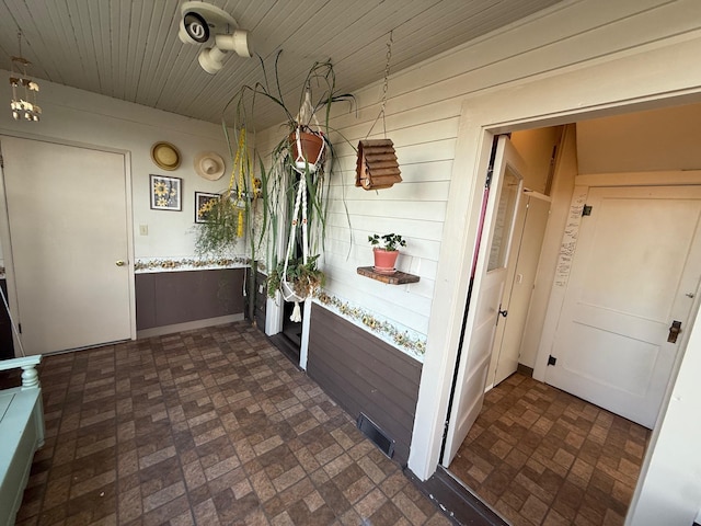 interior space featuring wooden ceiling, wood walls, visible vents, and light countertops