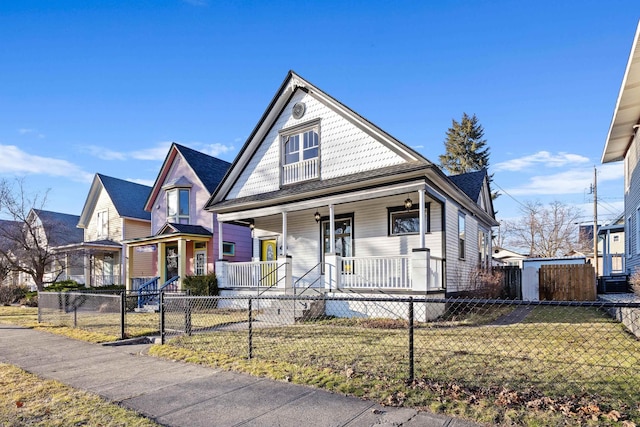 victorian home featuring a porch, a fenced front yard, and a front yard