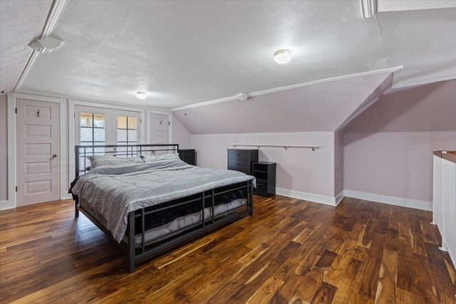 bedroom featuring a textured ceiling, vaulted ceiling, wood finished floors, and baseboards