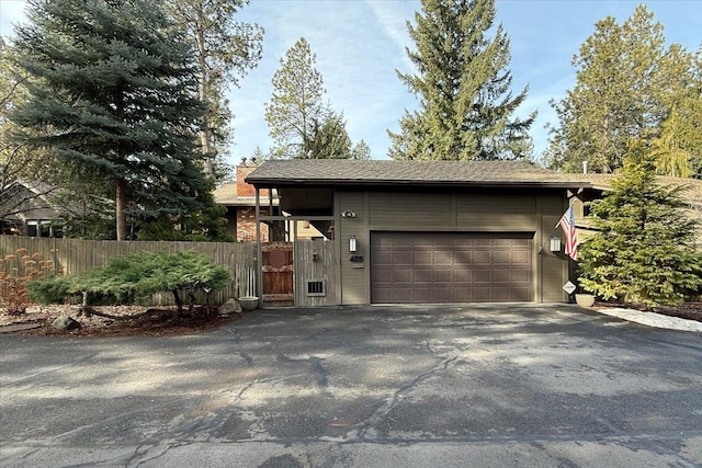 view of front facade with driveway, an attached garage, and fence