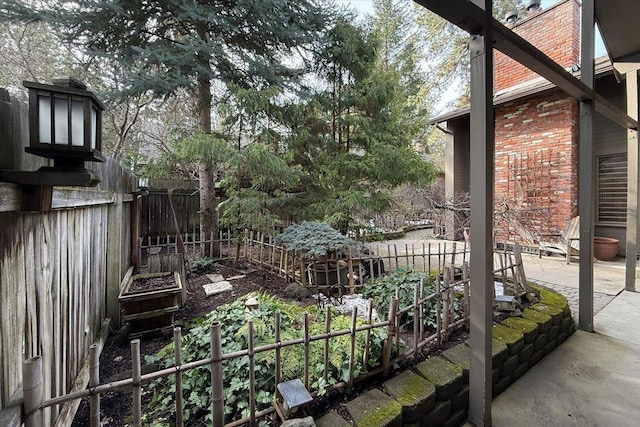 view of yard featuring a garden, fence, and a patio