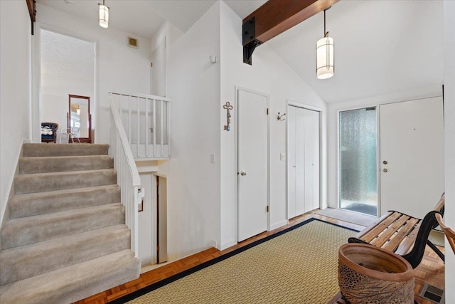 foyer featuring visible vents, vaulted ceiling with beams, and stairs