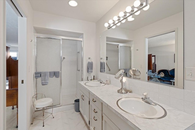 ensuite bathroom with a stall shower, double vanity, a sink, and ensuite bathroom