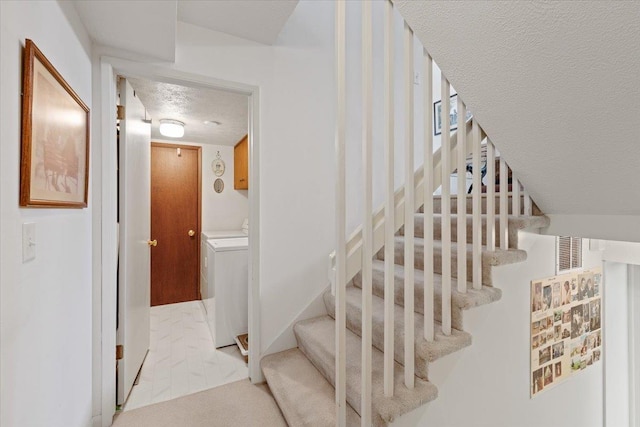 stairs with a textured ceiling, washer and clothes dryer, and visible vents