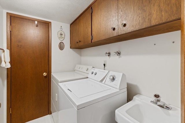 laundry area featuring cabinet space, a textured ceiling, a sink, and washing machine and clothes dryer