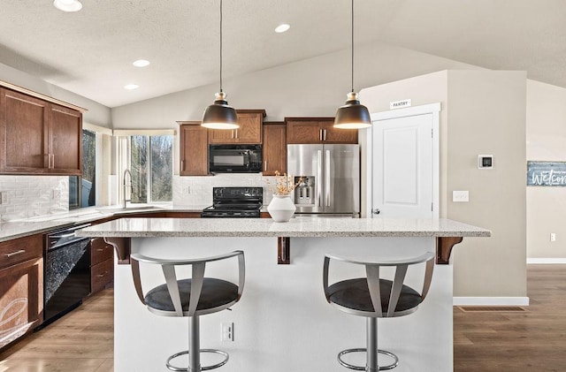 kitchen featuring light wood-style floors, lofted ceiling, a sink, and black appliances