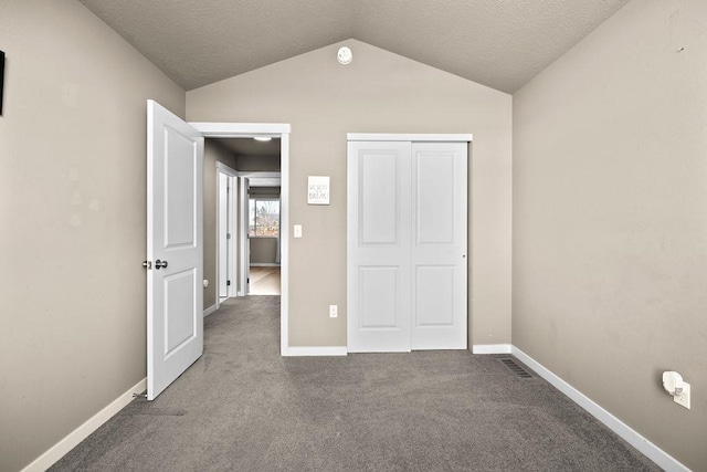 unfurnished bedroom with baseboards, visible vents, vaulted ceiling, and carpet flooring