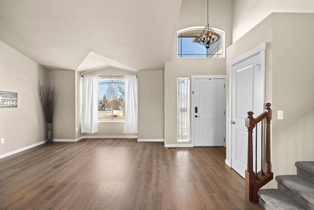 entryway featuring dark wood-type flooring, a chandelier, stairway, and baseboards