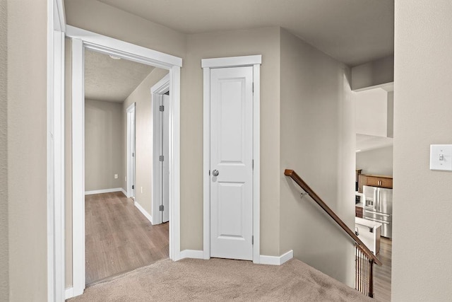 hallway with carpet flooring, an upstairs landing, and baseboards