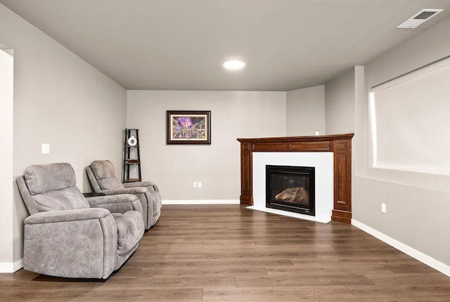 living room with baseboards, visible vents, and wood finished floors